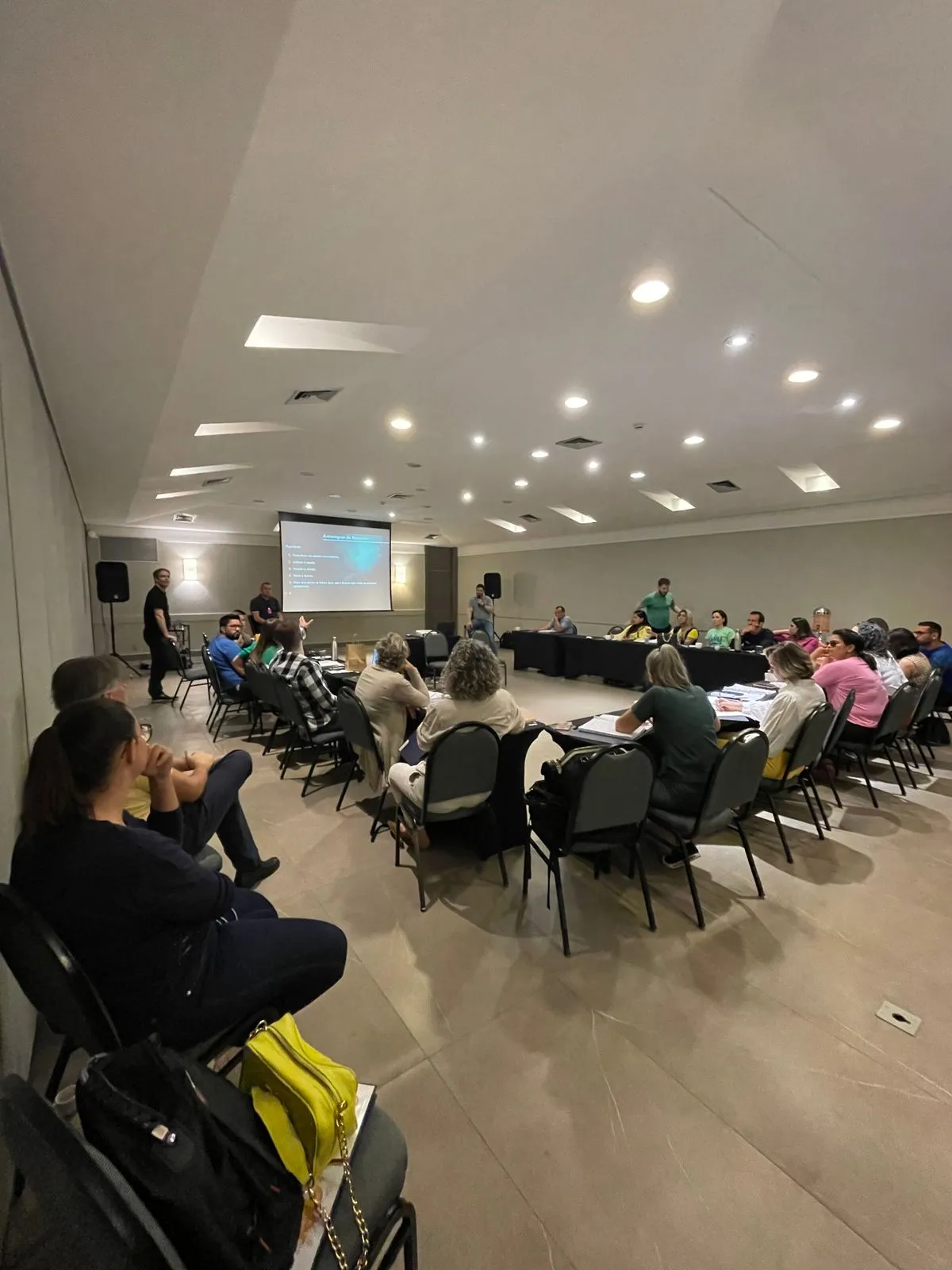 Sala de treinamento com participantes reunidos em grupos